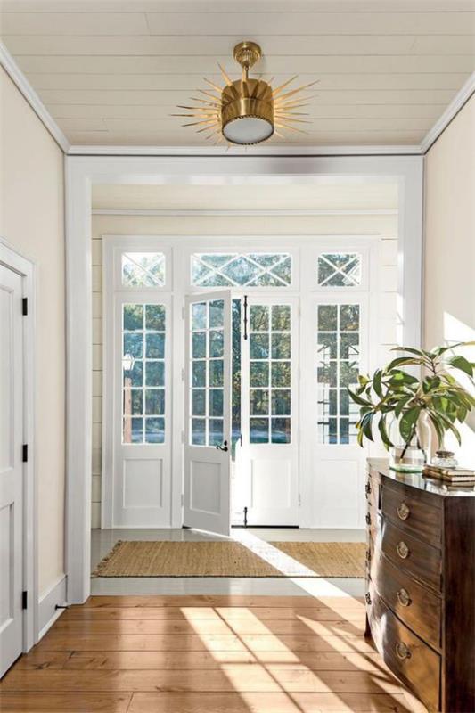 Francuskie okna francuskie biała rama tafli szkła dodaje dużo naturalnego światła do wnętrza przedpokoju domu bardzo elegancko zaprojektowanego dobrze doświetlonego.