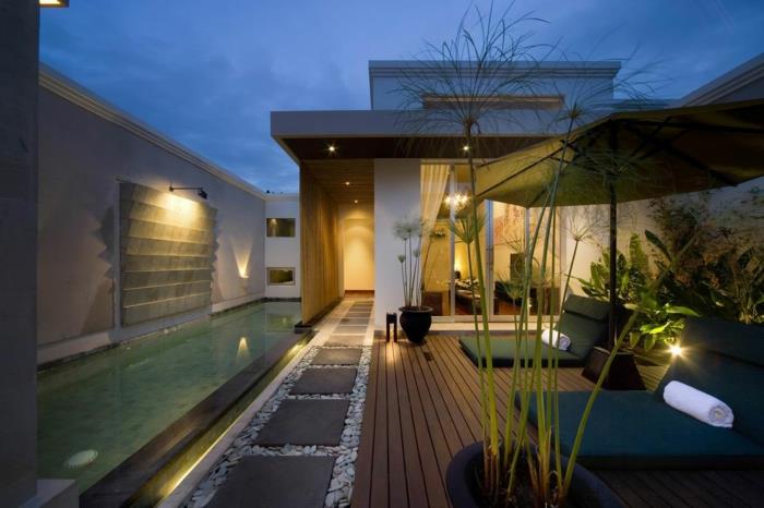 oświetlenie ogrodowe kinkiety basen zewnętrzny kamienie naturalne drewniane deski podłogowe parasol leżący