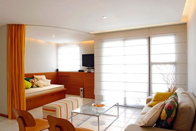 Flexibilní záclonová tyč v obývacím pokoji se složitou stropní konstrukcí ze sádrokartonu jako předěl místnosti do dvou zón. Hlavní výhodou pružné záclonové tyče je snadný a nerušený pohyb prvků záclonové tyče.