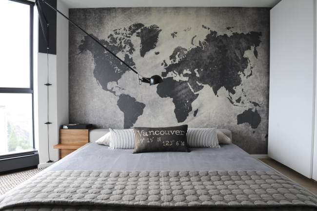 Atmosférická loftová ložnice. Grafická mapa světa ode zdi ke zdi zdůrazňuje jednobarevný interiér