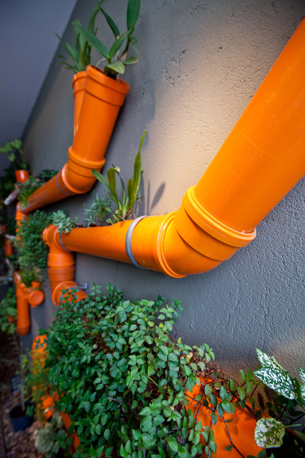 Jasně oranžové potrubí s rostlinami - neobvyklá kompozice, která může proměnit interiér