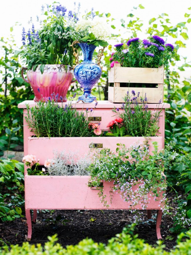 Stará komoda broskvové barvy s květinami zasazenými do krabic zaujme své správné místo v krajině letní chaty