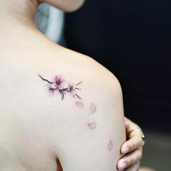 mały tatuaż z kwiatem wiśni sakura na ramieniu