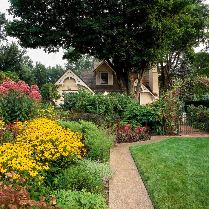 mały kształt ogrodu piękny dom wiele kolorowych kwiatów ogrodowych ścieżka ogrodzenia zielone krzewy wysokie drzewo