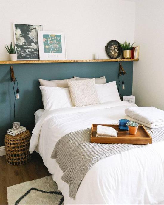 La petite chambre agrandit optiquement le mur d'accent turquoise contrastant avec le linge de lit blanc