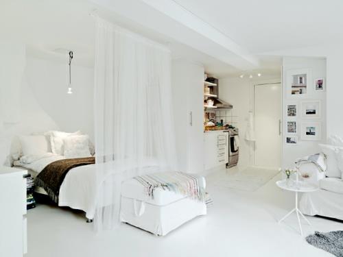 małe mieszkanie pokazuje rozmiar przezroczystych białych zasłon na łóżku