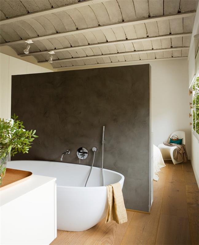 Mała łazienka z wyposażeniem wanna wolnostojąca owalny kształt betonowa ściana działowa sypialnia łazienka