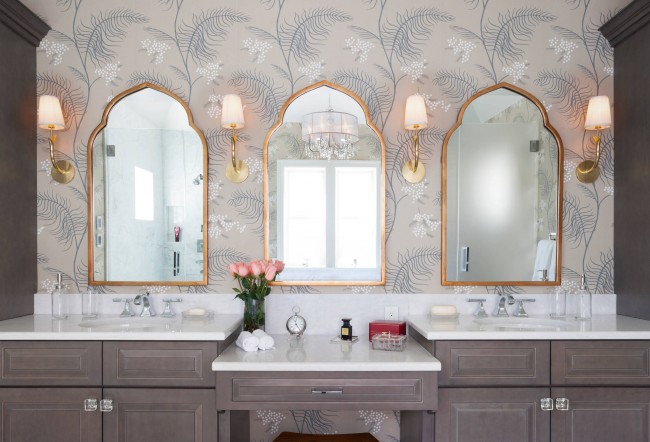 Ein neutrales Bad mit mediterranem Flair durch die Form der Spiegel und das florale Muster auf der Tapete