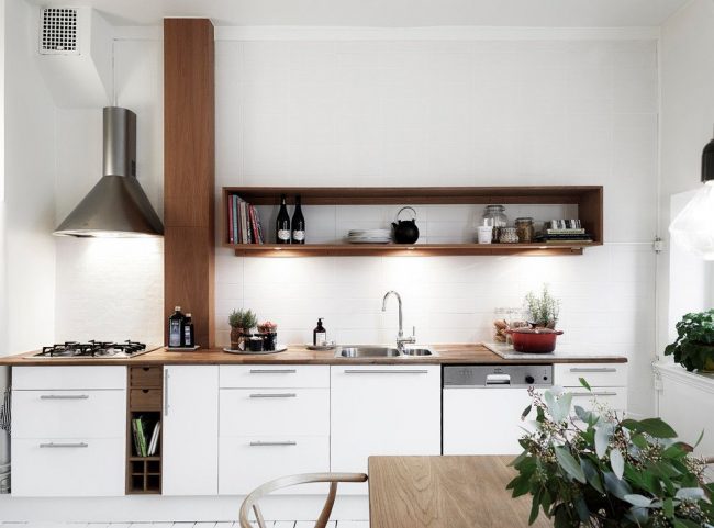 يعد المطبخ الأبيض مع ملحقات الأثاث البني الصغيرة حلاً قياسيًا للأسلوب الاسكندنافي