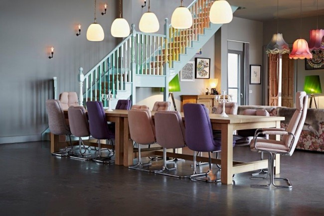 Hravou náladu obývacího pokoje vytváří jeho barevné schéma, zejména fialové židle v různých odstínech.
