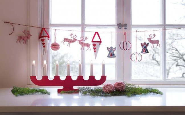 Червеният свещник и елементи от висящи играчки ще разреждат снежнобялата перваза на прозореца