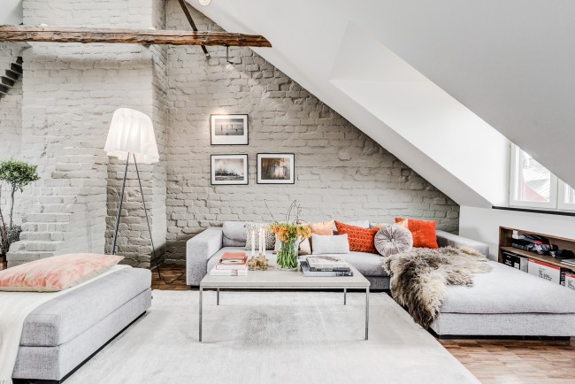 Jasně oranžové akcenty na polštářích zředí bílý obývací pokoj