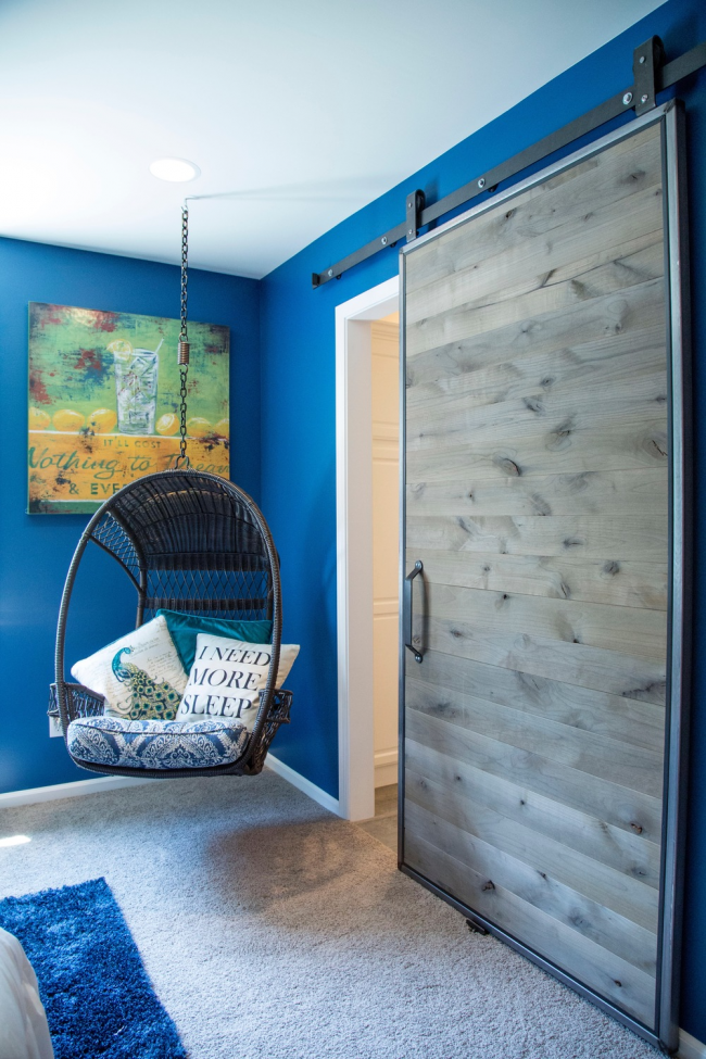 Die Schiebetür mit gräulichem Holzblatt harmoniert perfekt mit der leuchtend blauen Farbe der Zimmerwände