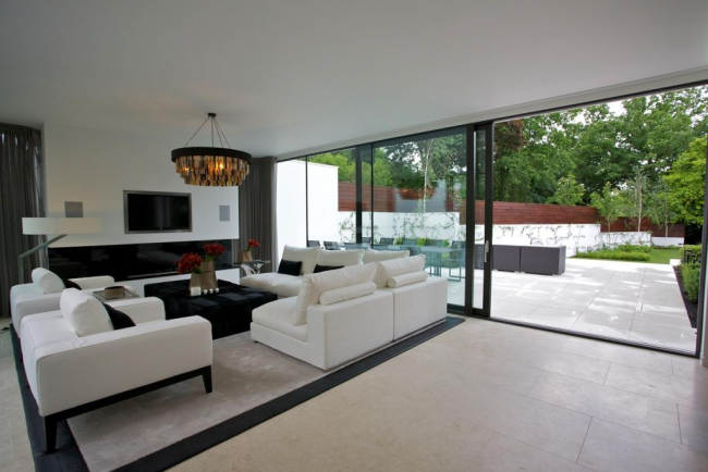 Große Glasschiebetüren in einem Privathaus harmonieren perfekt mit dem allgemeinen Interieur eines geräumigen Wohnzimmers