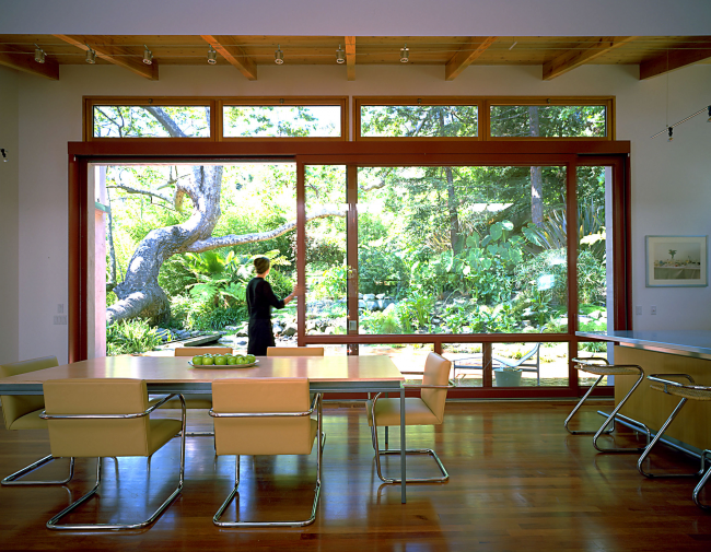 أبواب منزلقة ضخمة مصنوعة من الخشب الطبيعي والزجاج في منزل ريفي خاص تخلق حقًا شعورًا بمساحة هائلة حقيقية