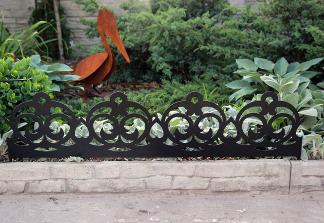 Декорация на малка цветна леха под формата на кована ограда