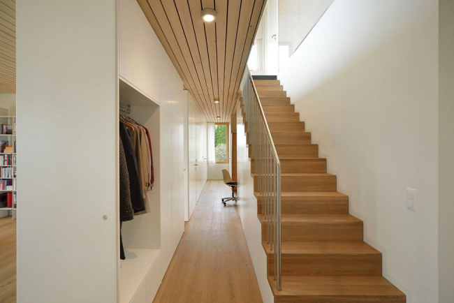 Světlý moderní interiér s dřevěným schodištěm a nerezovým zábradlím