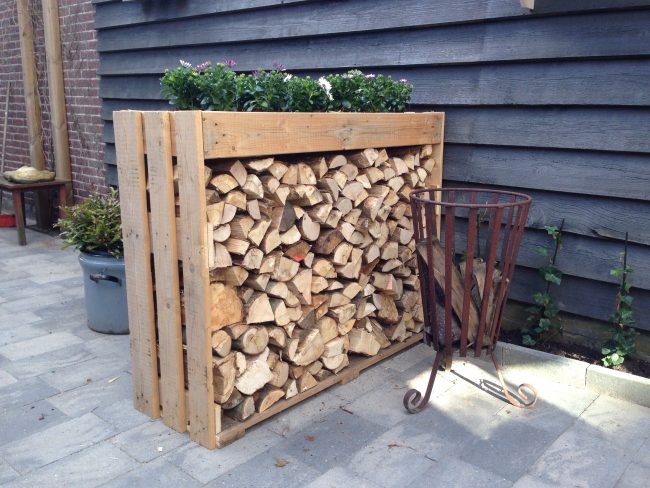 Ein kleiner Holzstapel für Brennholz, vor dem Haus auf einem Betonpflaster platziert