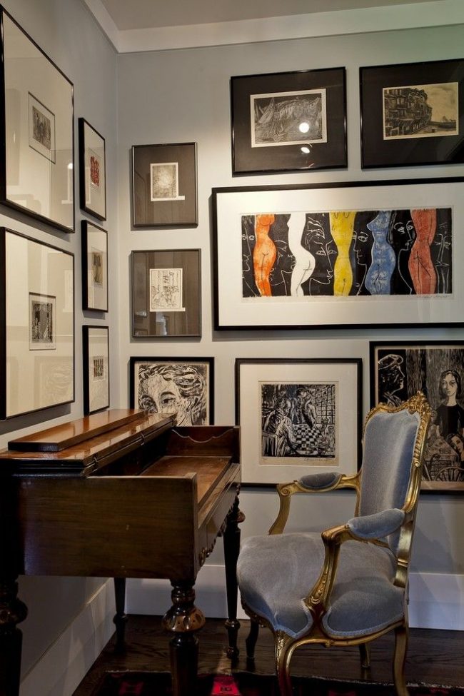 Home Office mit Vintage-Möbeln: ein lackierter Tisch mit geschnitzten Beinen und ein klassischer Samtsessel. Kontrastierende schwarze Rahmen an einer hellgrauen Wand