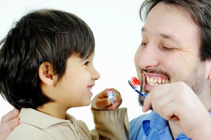 właściwa opieka stomatologiczna ojciec i syn myją zęby
