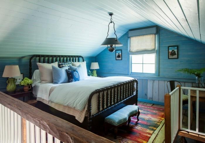 sypialnia w stylu wiejskim niebieska ściana akcentująca i spadzisty sufit