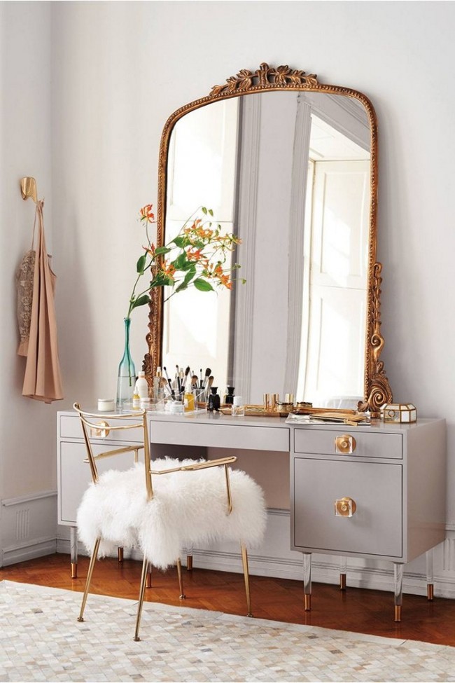Ein riesiger Spiegel mit geschnitztem Rahmen und ein Fellumhang auf dem Stuhl machen den Ankleidebereich eleganter