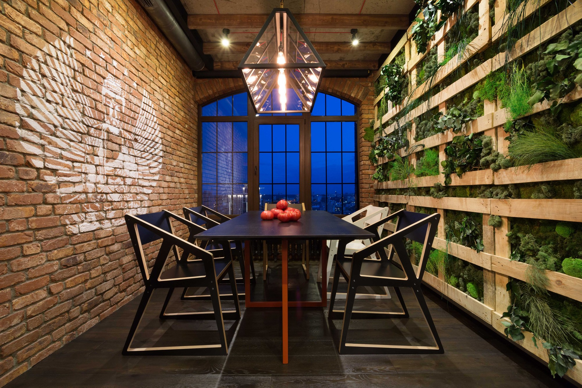 Лаконична трапезария в стил таванско помещение от групата дизайнери на MARTIN архитекти: тухлена стена с противоположна растителност, черен под, минималистични мебели, геометрична структура на осветление