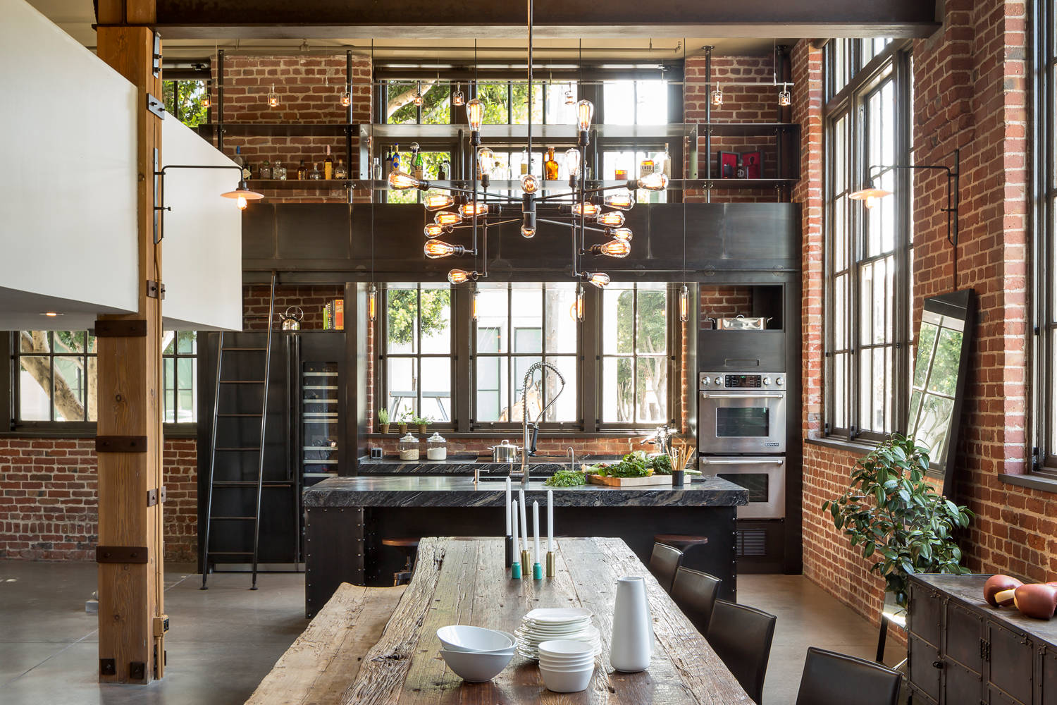 Eine charakteristische Küche im Loft-Stil mit viel Ziegel, Holz und Metall in der Dekoration. Edison-Leuchten in kombinierten Stromschienen-Designs und Wandleuchten unterstreichen das Gesamtthema