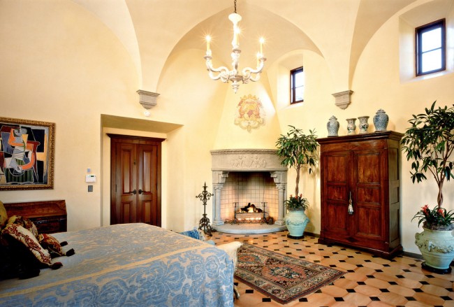 Krásný krb, zdobený štukem, v interiéru ložnice ve středomořském stylu