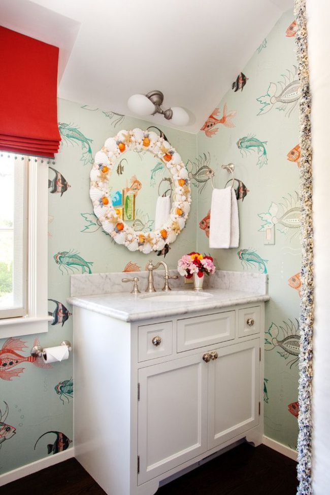 Koupelna s mořským motivem a jemnou pastelovou tapetou s grafickými obrázky různých druhů ryb. Ručně vyráběné skořepinové zrcadlo - funkce interiéru