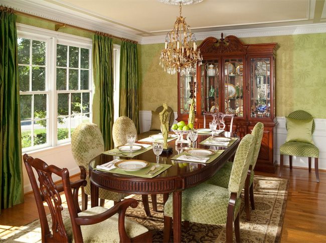 Klasický interiér jídelny s vyřezávaným dřevěným nábytkem, saténovými závěsy a polštáři, sochami, zlatým lustrem a dalším luxusním vybavením