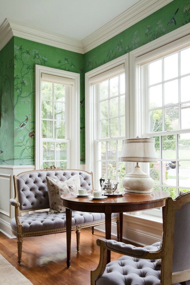Tradiční americká jídelna: úzká vysoká okna s římskými odstíny, elegantní pohovky, lakovaný dřevěný stůl a zelené vzorované tapety
